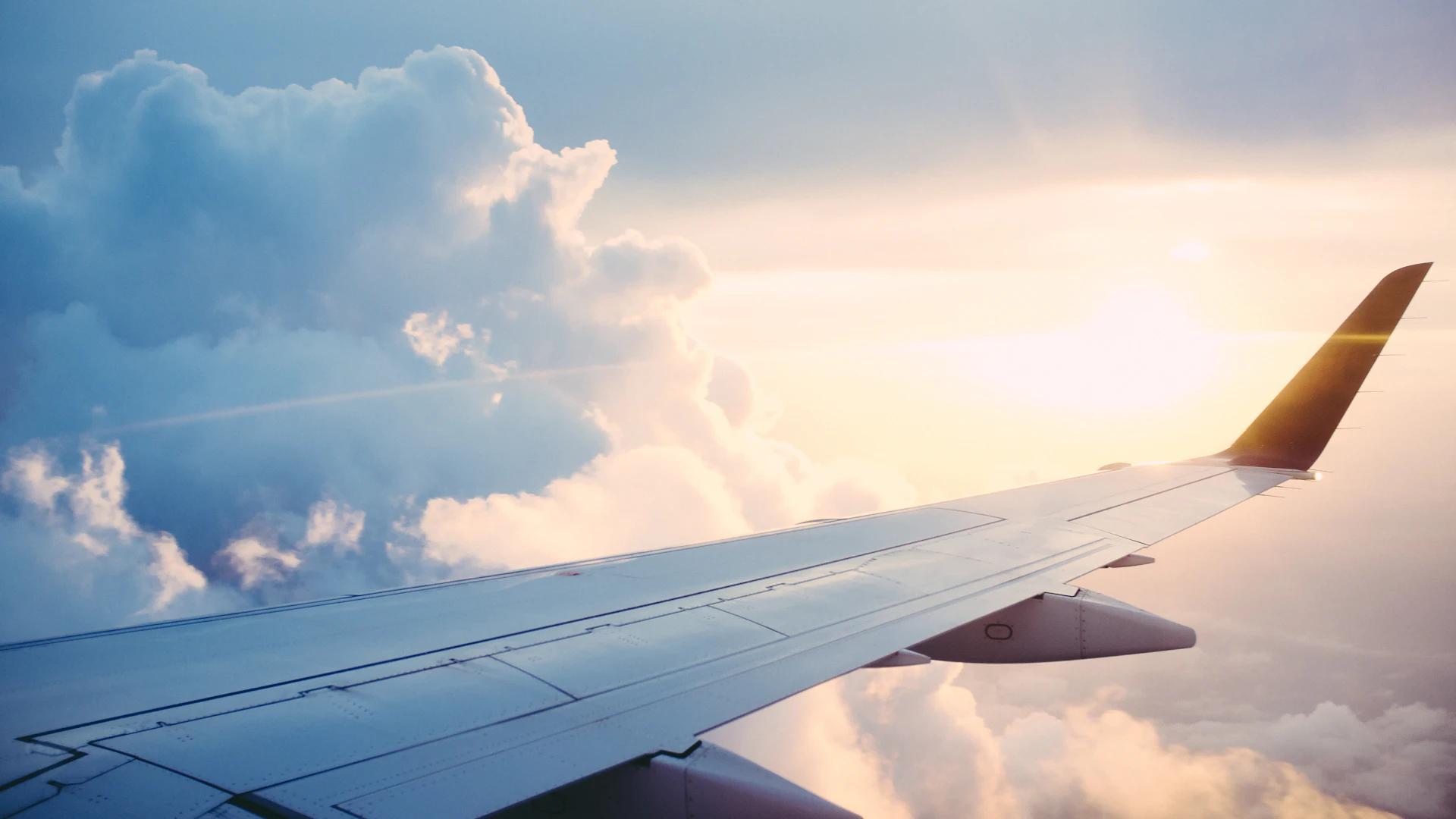 Flugzeugflügel über den Wolken bei Sonnenuntergang
