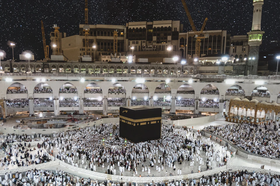 Die Kaaba in Mekka bei Nacht, umgeben von Pilgern